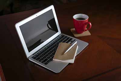 laptop computer and notebook with coffee cup on desk